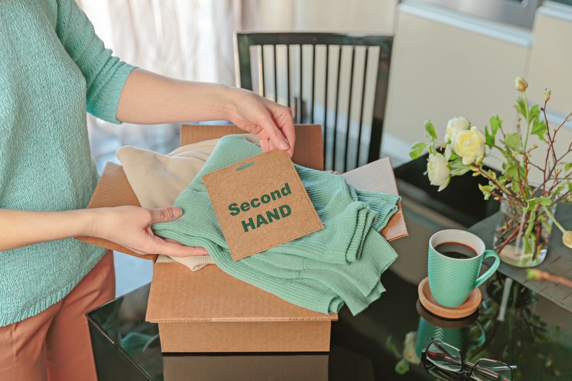 Woman packing box with used clothes for resale